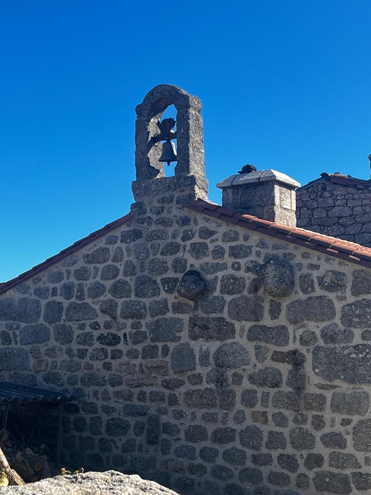 Façade et clocher d’une chapelle en pierre sous un ciel bleu