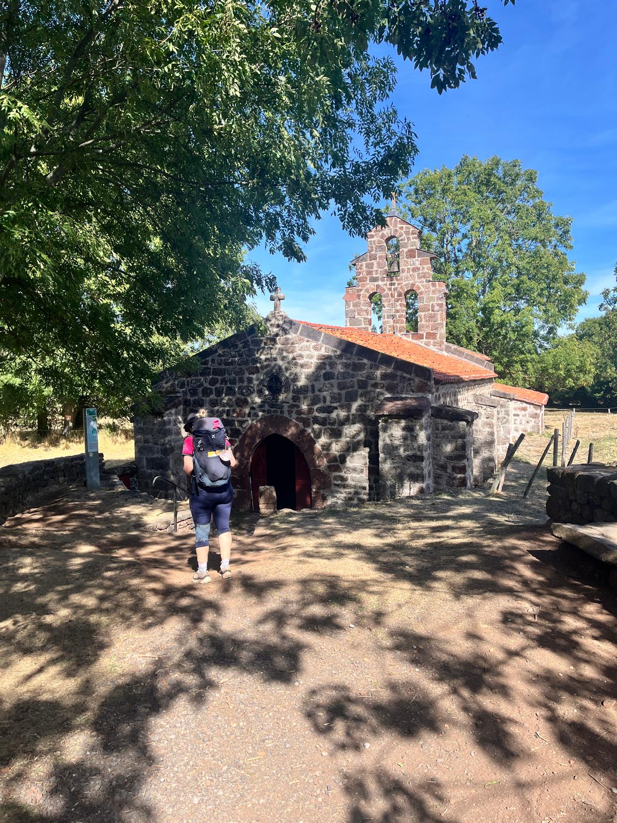 Participante devant une petite chapelle en pierre sur le chemin