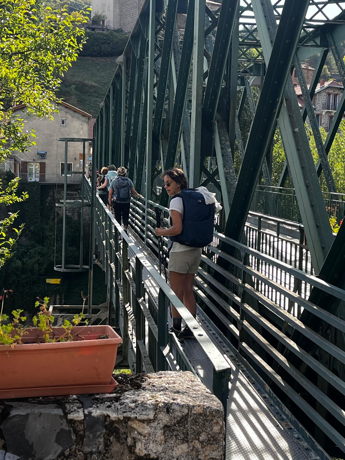 Les participantes traversent un pont métallique au-dessus de la rivière