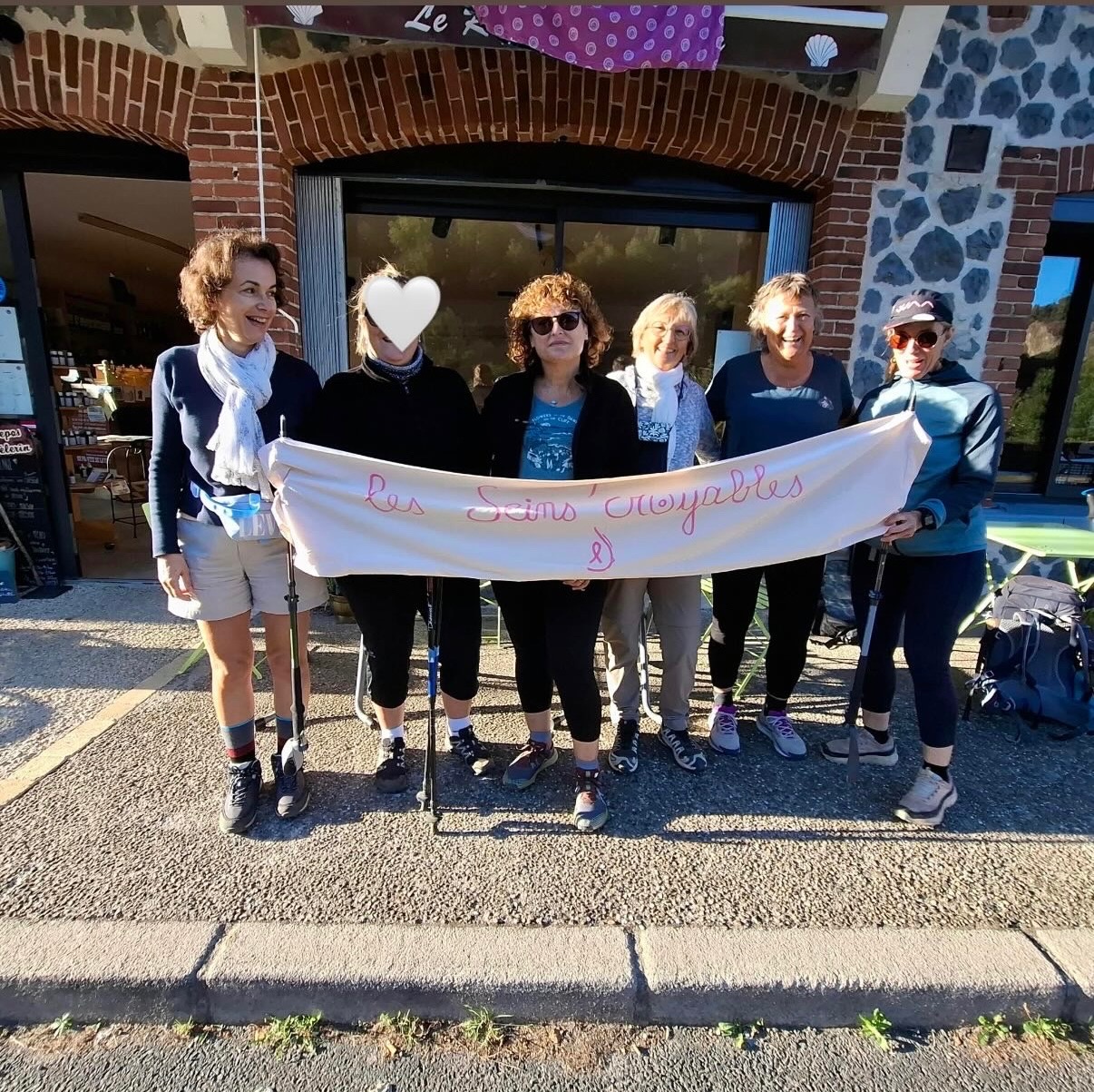 Les six participantes des Seins’Croyables avec leur banderole devant un gîte sur le chemin de Compostelle