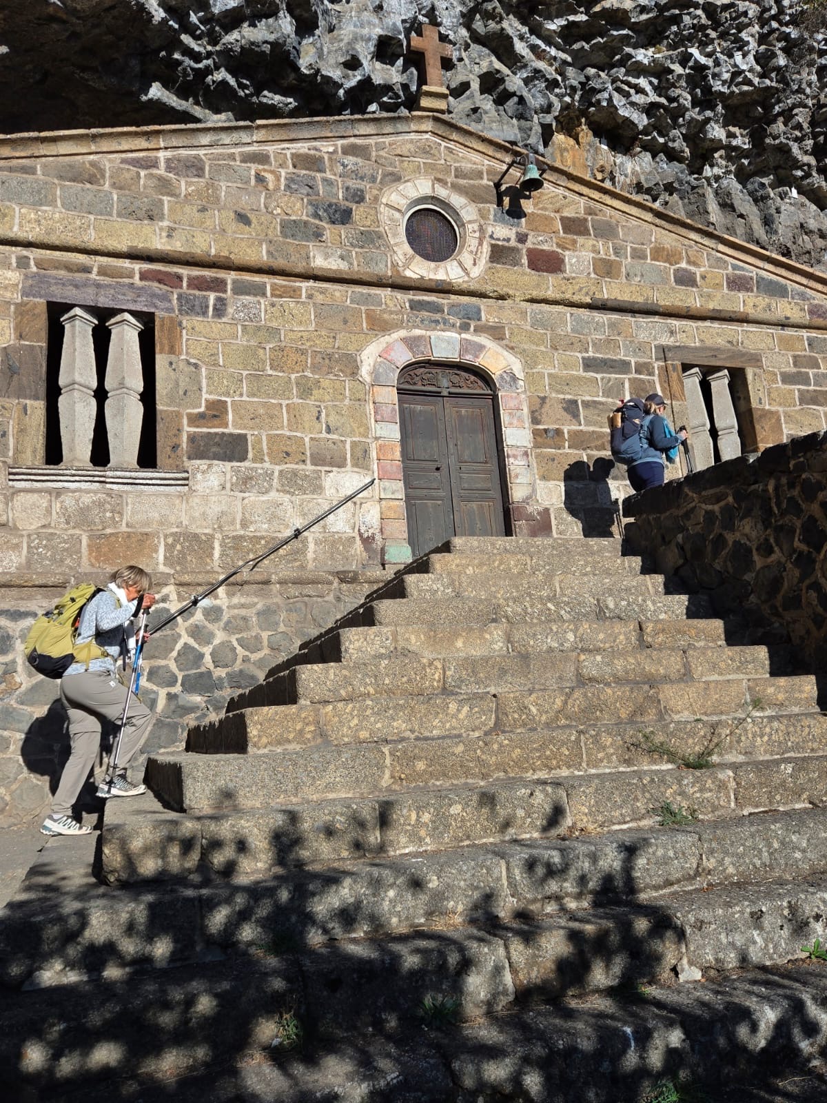 Chapelle de la Madeleine en pierre avec ses marches et randonneuses