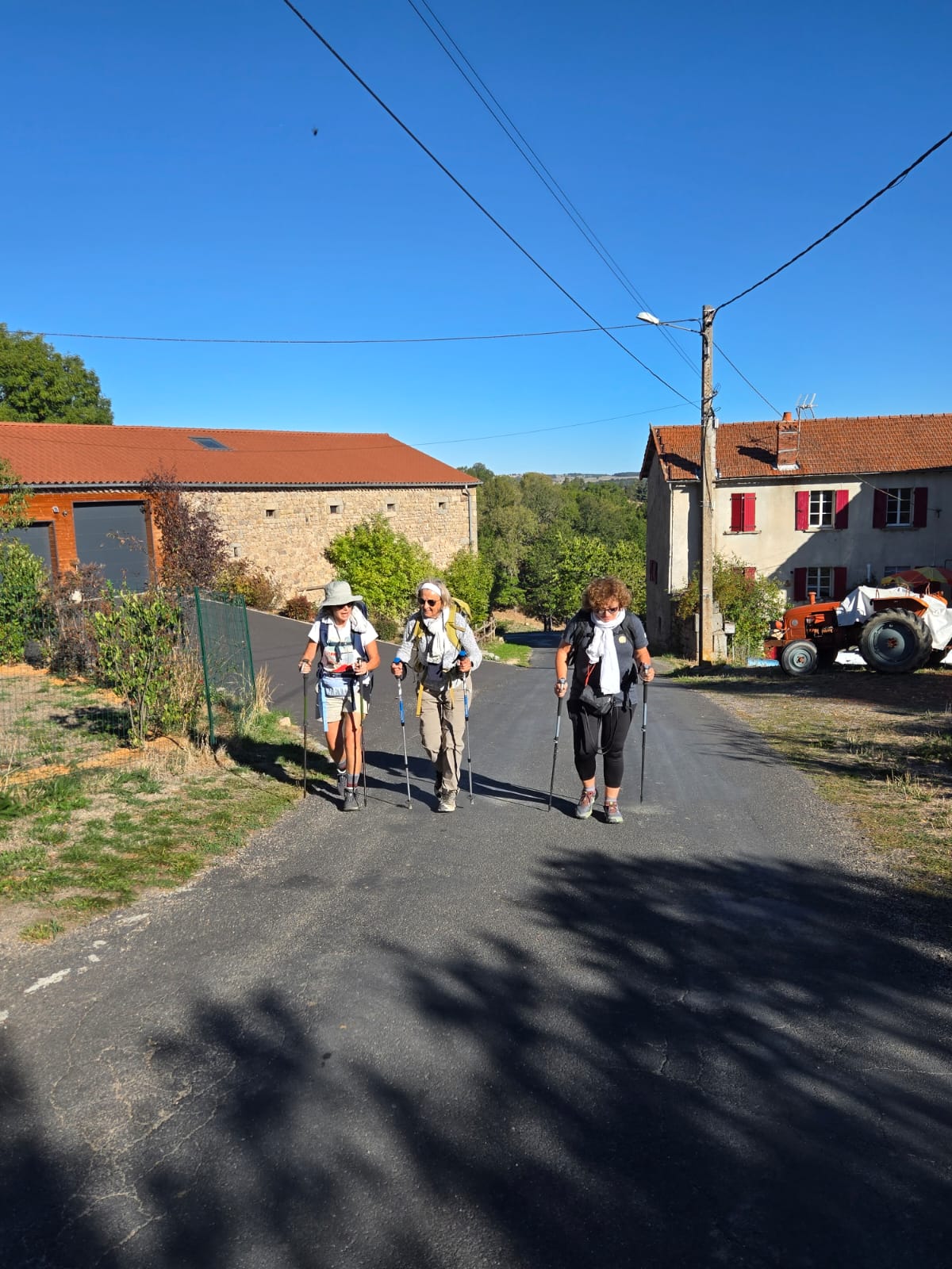Trois marcheuses gravissant une route dans un village