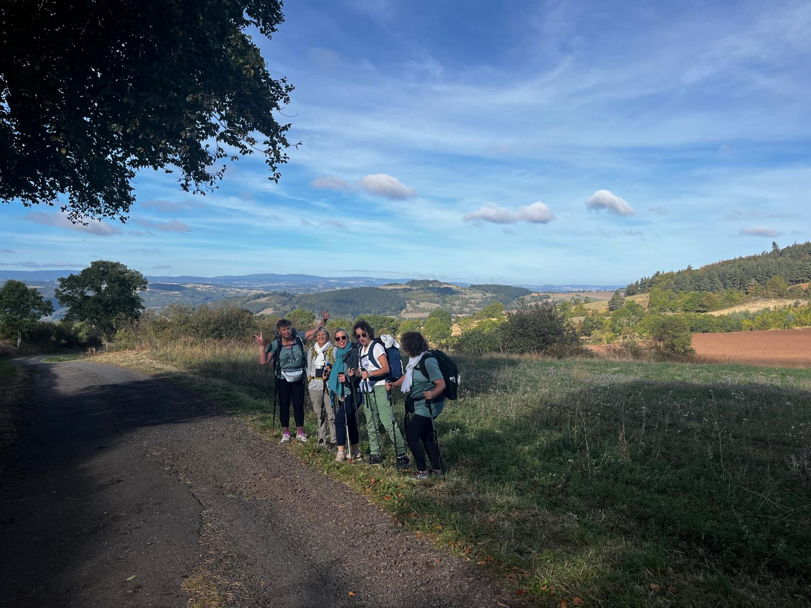 Les six participantes des Seins’Croyables posent sur le chemin de Compostelle, paysage vallonné en arrière-plan